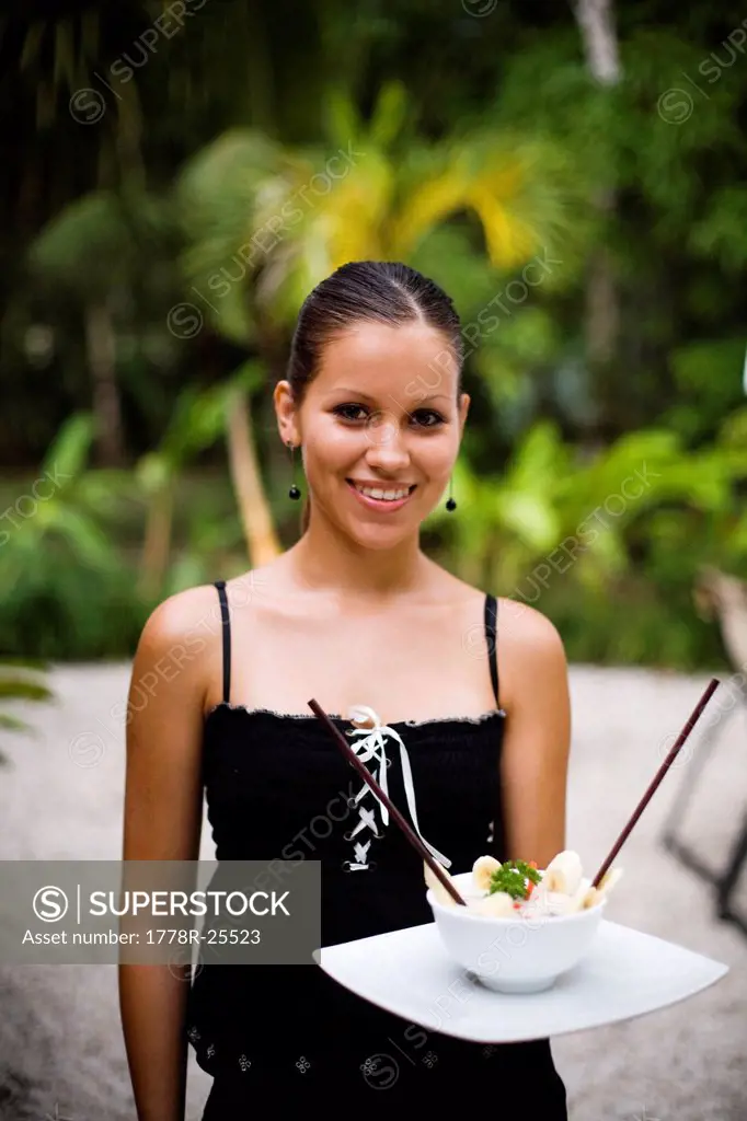 A portrait of a woman holding a bowl of ceviche.