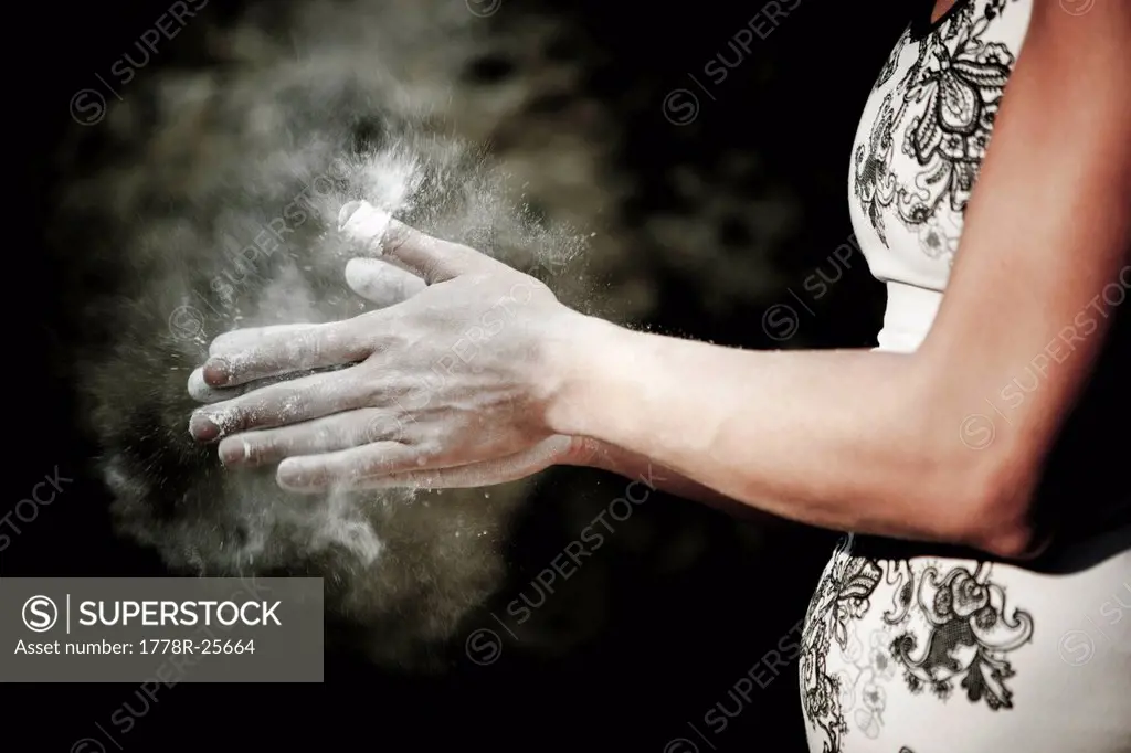 Female climber chalks her hands before climbing a bouldering route.