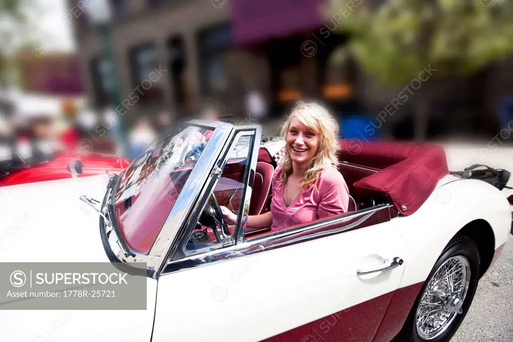 A beautiful young women smiles while sitting in a vintage car in Idaho.