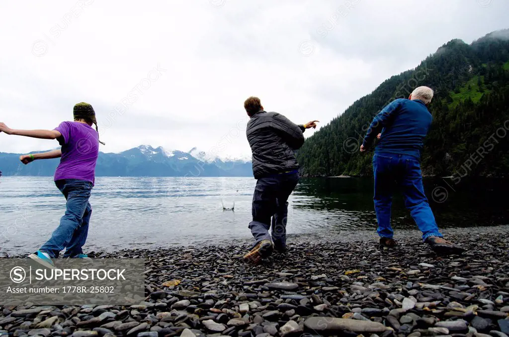 Three men have a rock_skipping contest on Fox Island, Alaska.