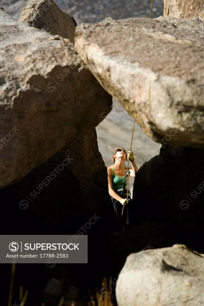 Female belaying between rocks.