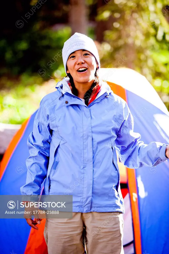 a woman smiles as she stands in front of her tent with a water bottle. The campsite is at Squaw Pass on the west side of the meadow.