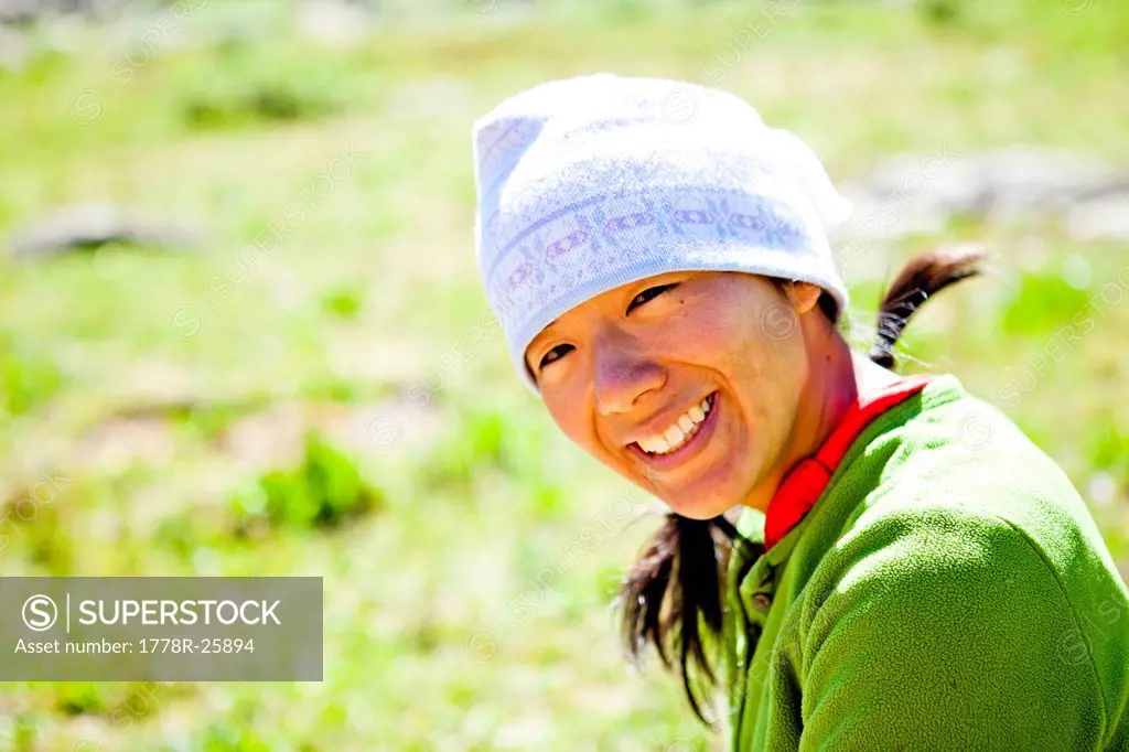 a woman smiles as she sits in an alpine meadow. She is just off the Continental Divide Trail CCT, trail number 813 just north of Squaw Pass at approxi...