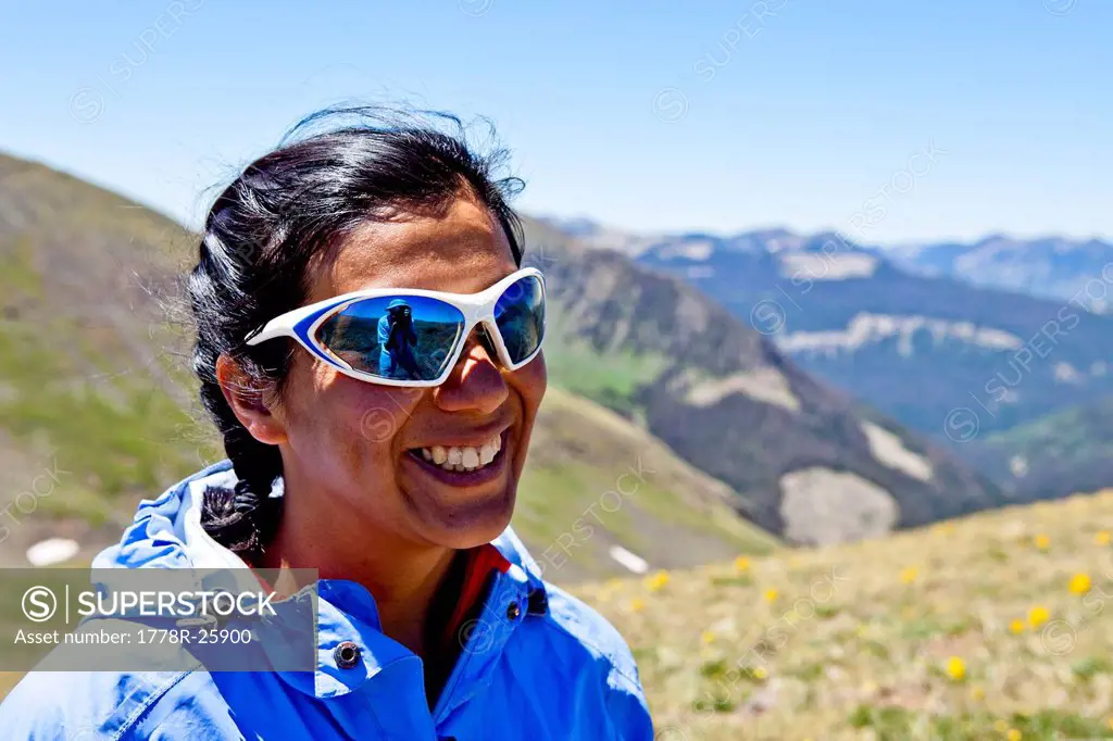 a woman smiles while vistas of the Rocky Mountains are behind her. She is on the Continental Divide Trail CCT, trail number 813 north of Squaw Pass at...