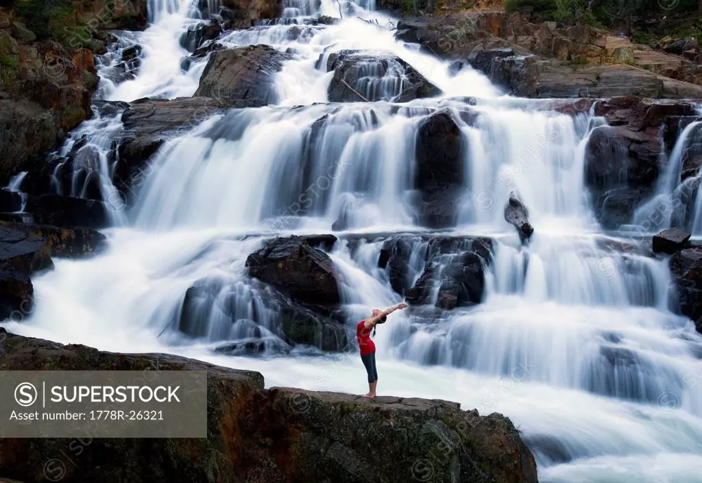 A woman performs yoga in front of a large waterfall in Lake Tahoe, California.