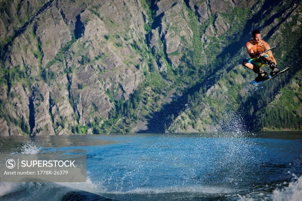 A athletic male wakeboarder boosts over the wake at sunset on a lake in Idaho.