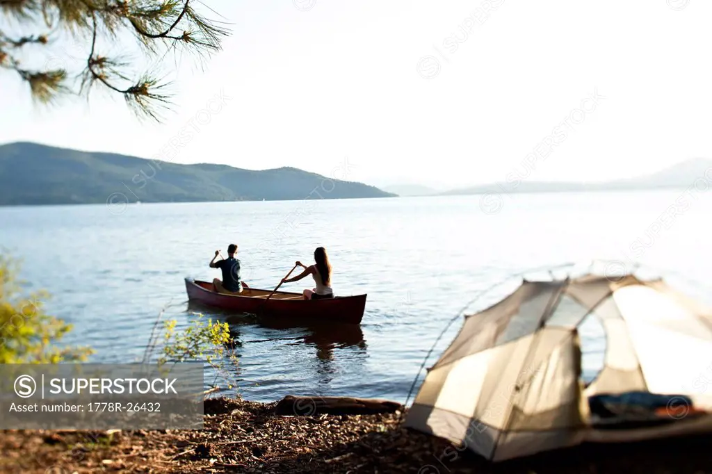 Two young adults canoeing on a camping trip next to a lake in Idaho.