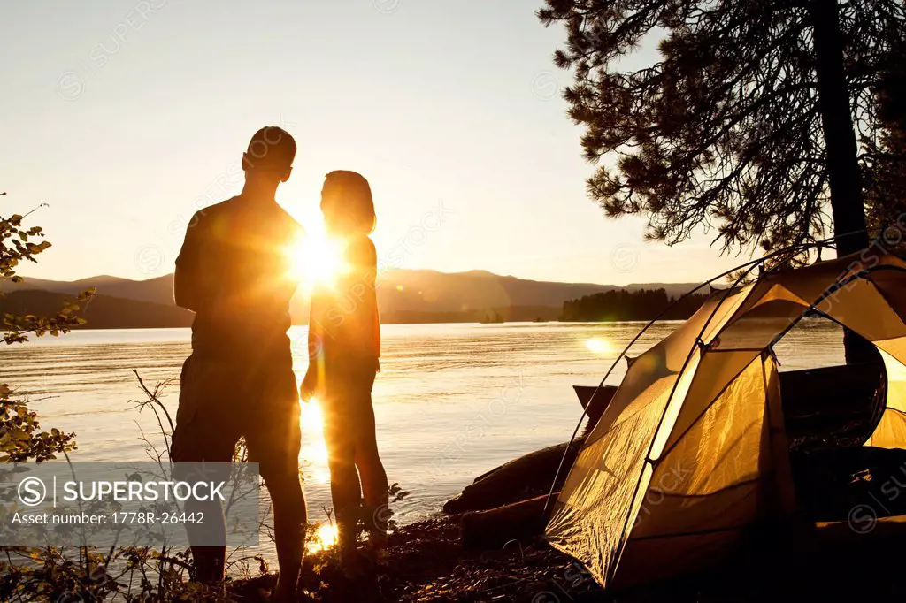 Two young adults laugh and smile at sunset on a camping and kayaking trip in Idaho.