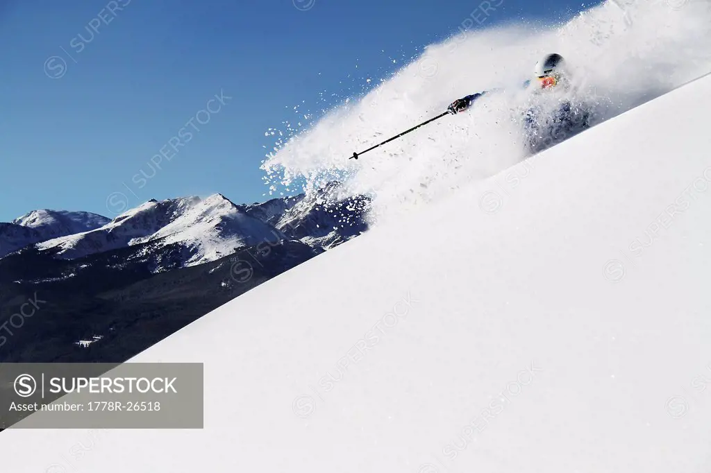 A athletic skier rips fresh powder turns on a sunny day in Colorado.