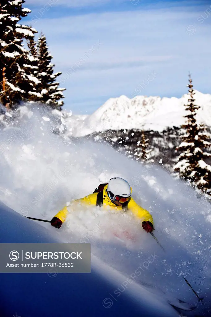 A athletic skier rips fresh powder turns in the backcountry on a sunny day in Colorado.