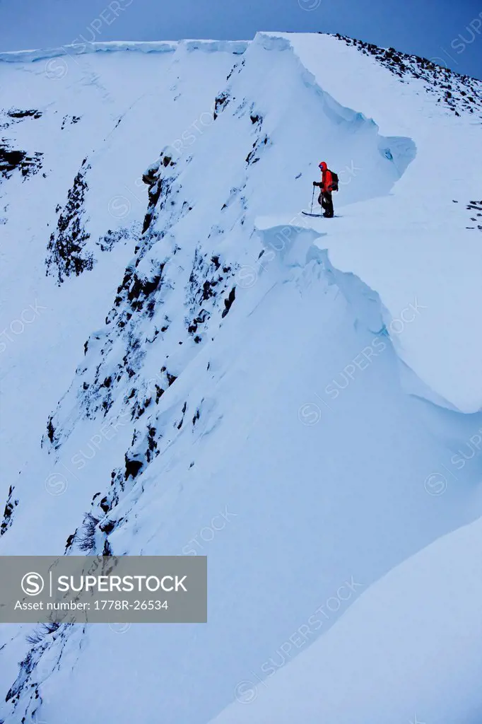 A athletic snowboarder hiking in the backcountry using a splitboard to hike up the mountain in Colorado.