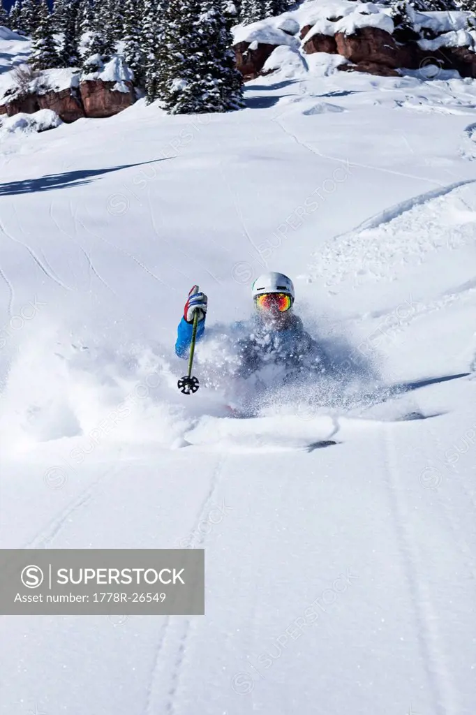 A athletic skier rips fresh powder turns in the backcountry on a sunny day in Colorado.