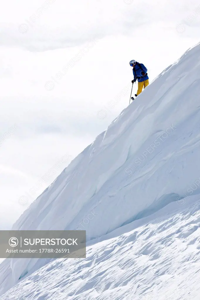 A skier scouts his line standing on top of a huge cornice in Colorado.