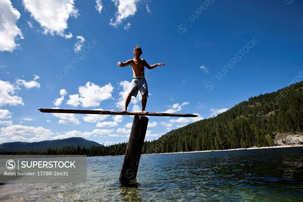 A young man balances on a teeter totters high above a lake in Idaho.