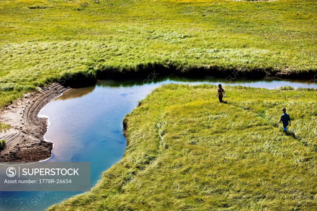 Two young men hike through a grassy field in Montana.