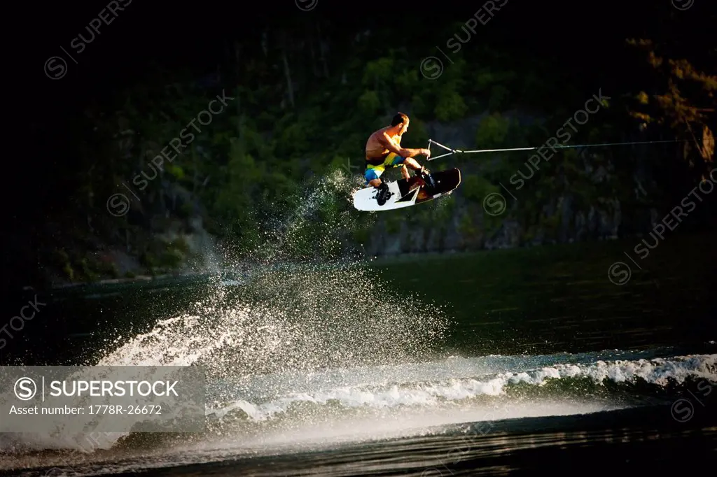 A athletic man wakeboarding jumps the wake going huge in Idaho.