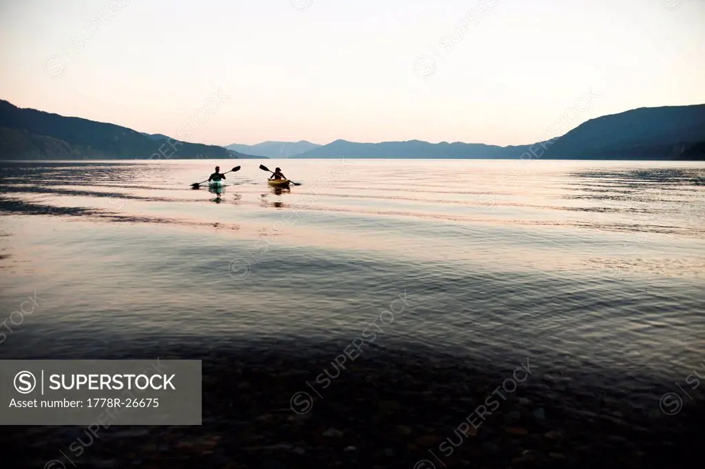 Two young adults kayaking on a lake in Idaho.