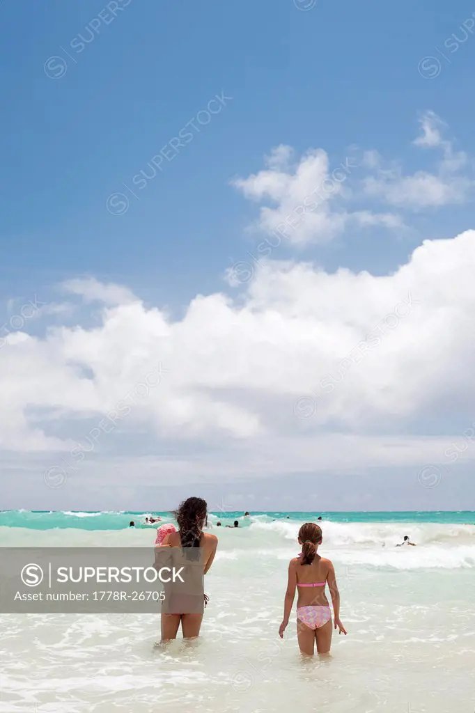 Two girls and a baby going into the sea in Kailua, Hawaii.