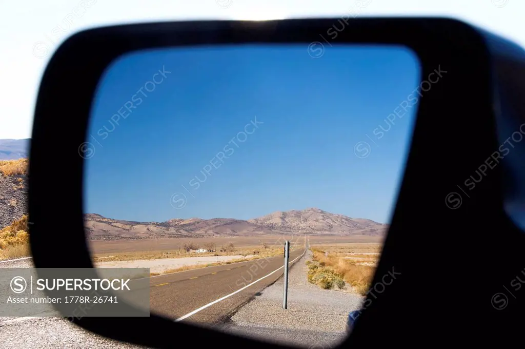 Highway 50 in Nevada, better known as the Loneliest Road in America, is reflected in a rearview mirror.