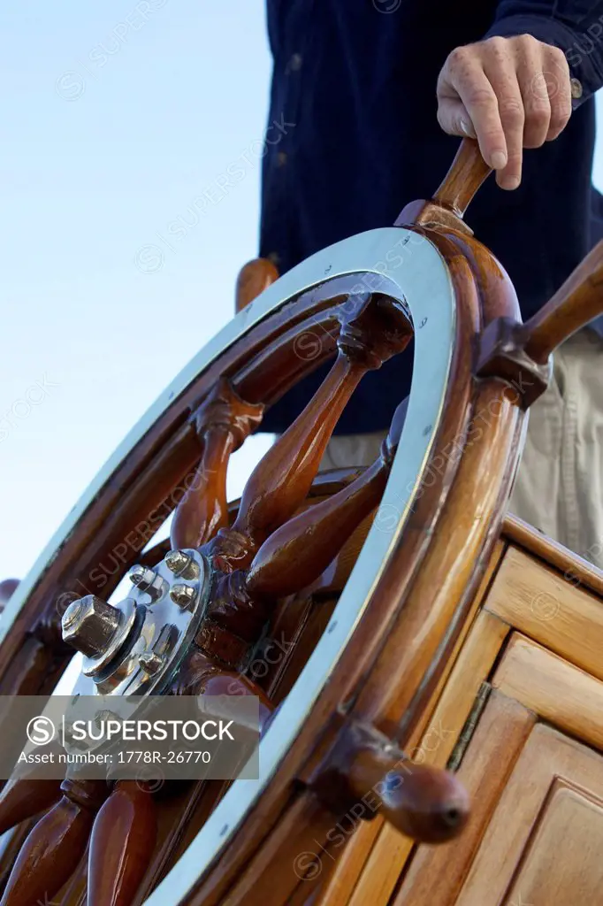 The captain keeps his hand on ship´s wheel on board the sailing yacht
