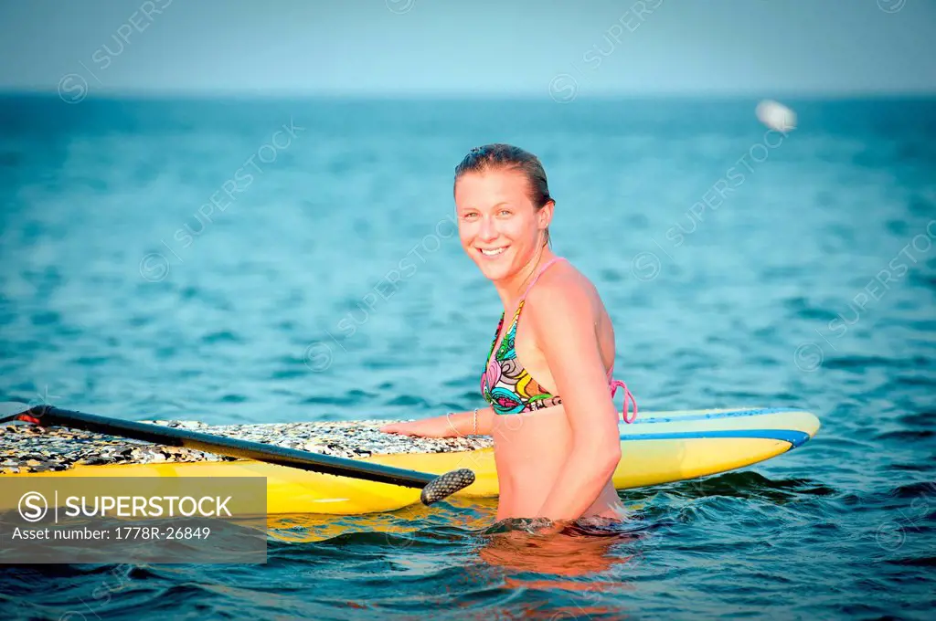 A young woman enjoys her stand up paddle board in the ocean.