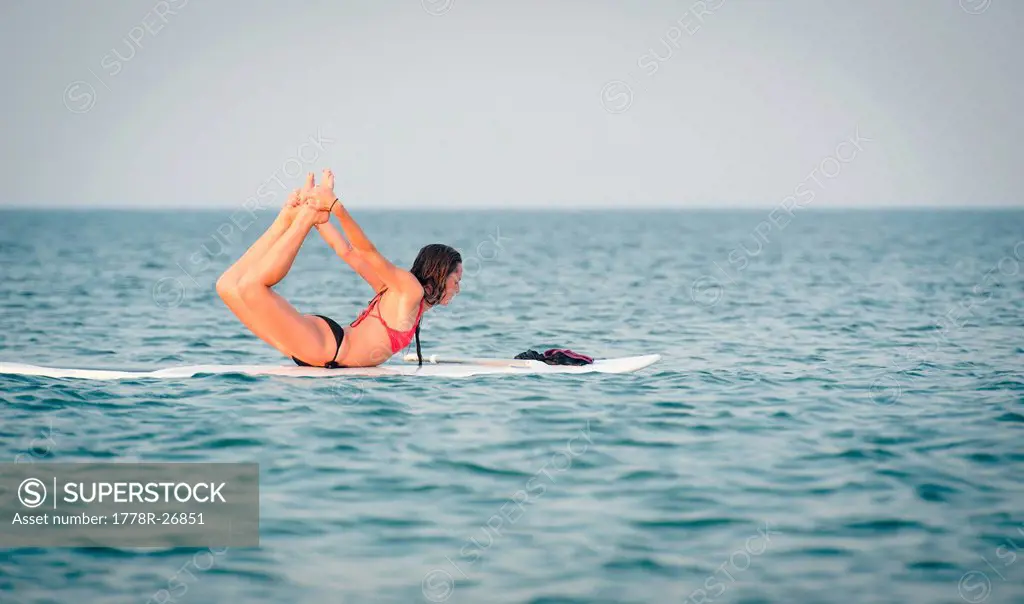 A young woman enjoys her stand up paddle board in the ocean.