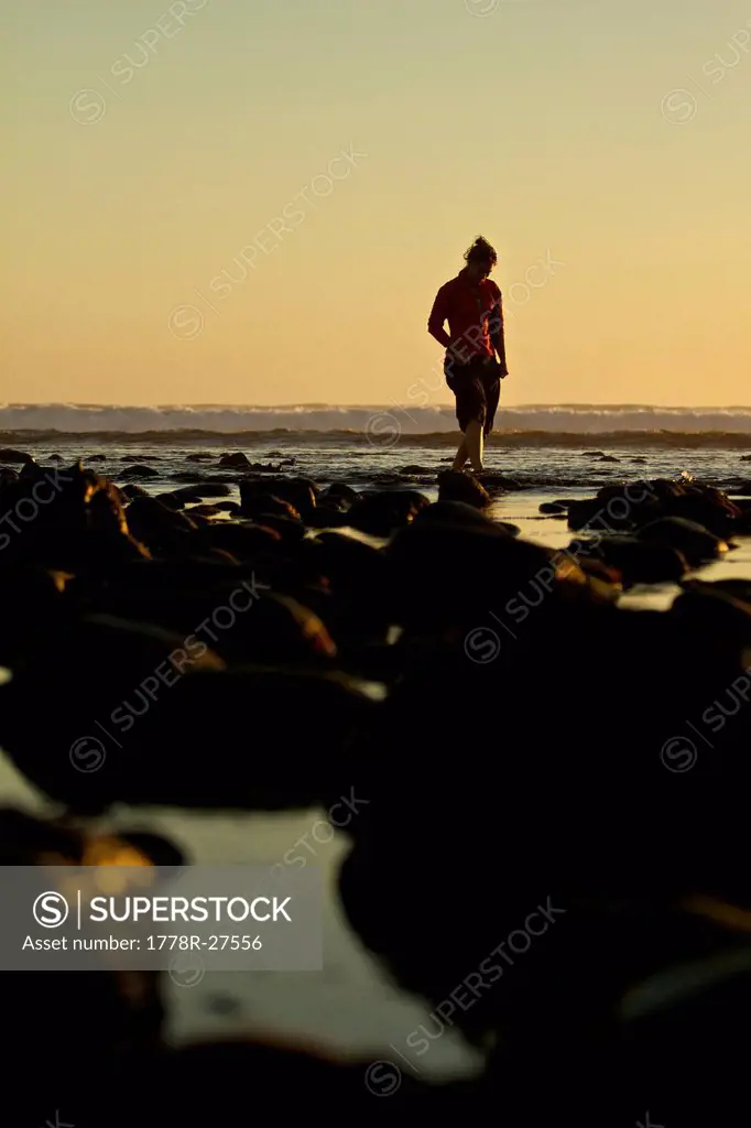 A female walks along the ocean shore at sunset during low tide on the Baja Peninsula Mexico.