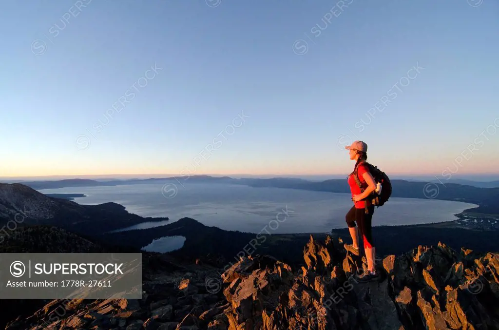 A female hiker enjoys a spectacular view of Lake Tahoe at sunset from the summit of Mount Tallac, CA.