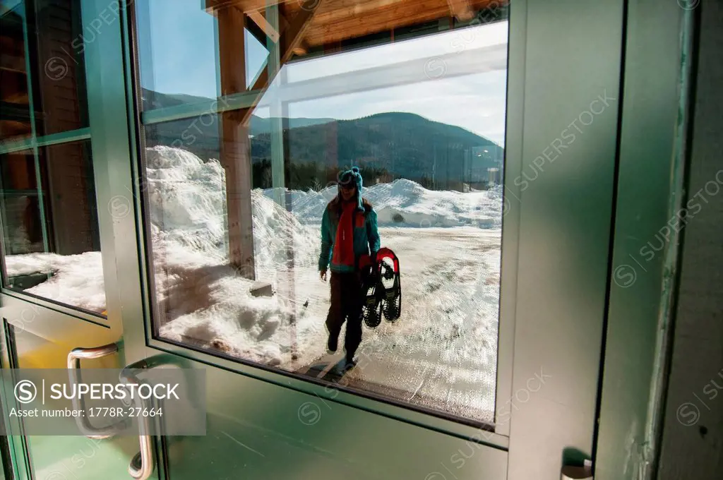 Woman carrying snowshoes into the Highland Center located in Crawford Notch, NH.