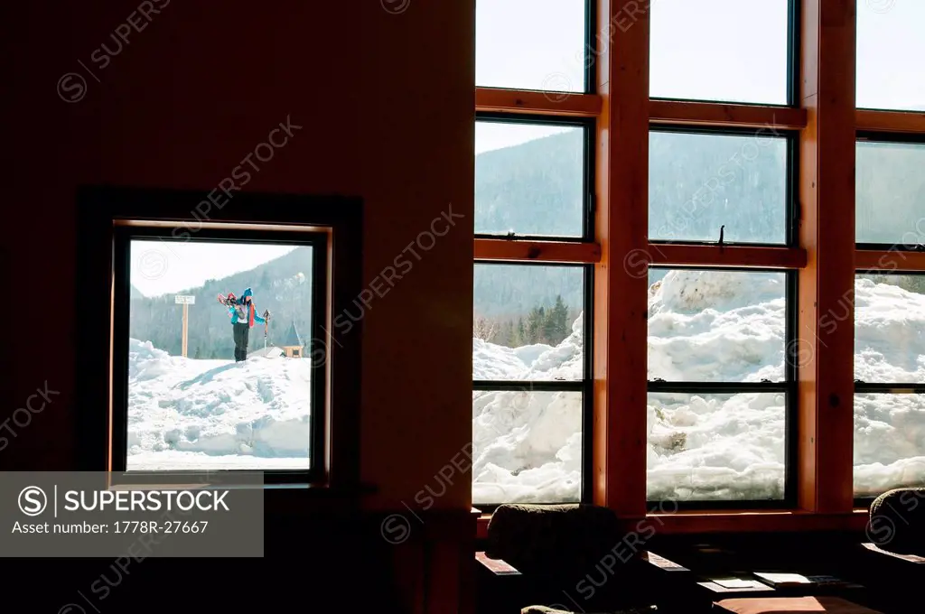Woman outside the door of a lodge with snowshoes and lots of snow.