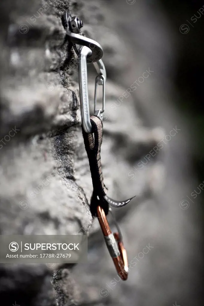 Rock climbing equipment hangs from a rock face.
