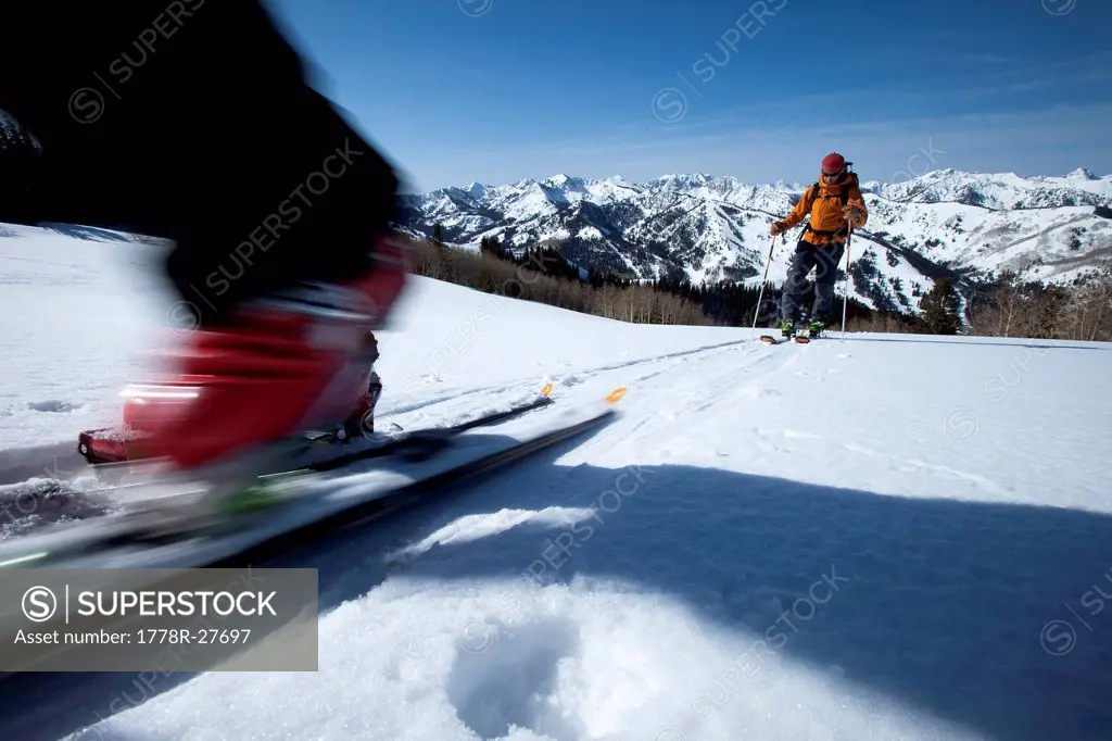 Low angle perspective of a skier´s boot motion blurred with a skier int he background.