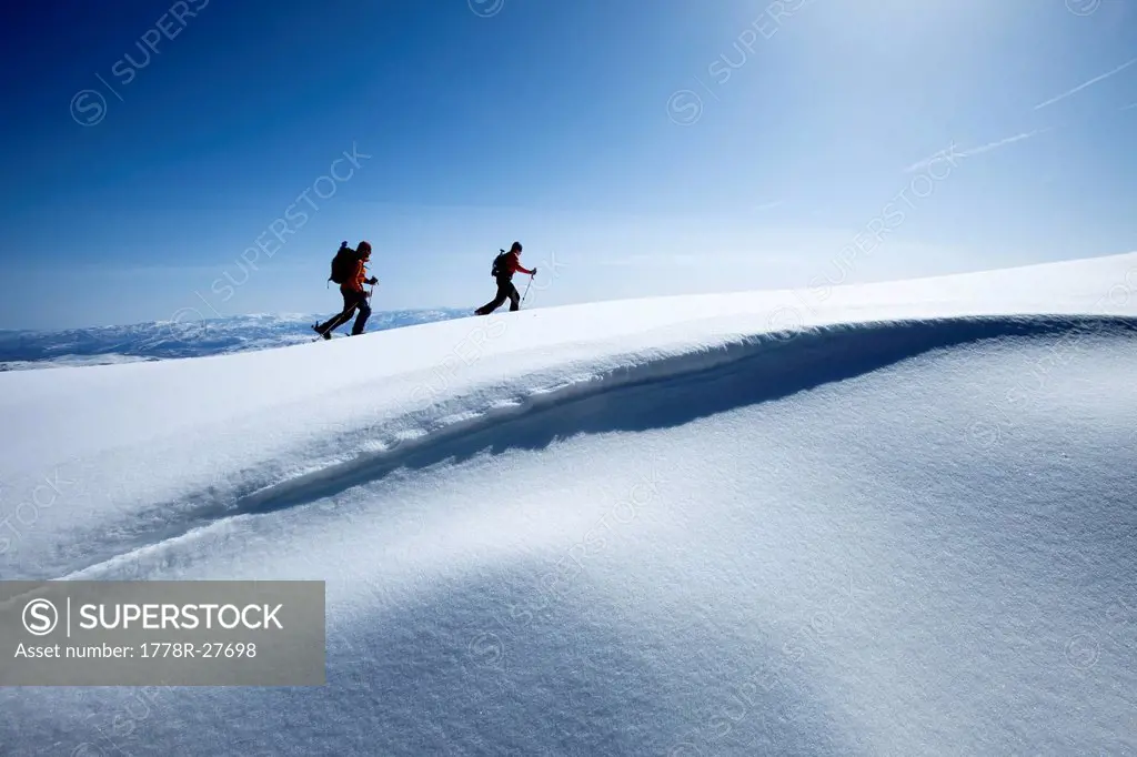 Two backcountry skiers hiking in fresh powder and bluebird skies.