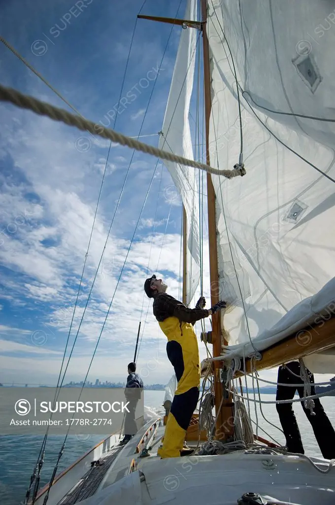 Man adjusts the rigging on his yacht.