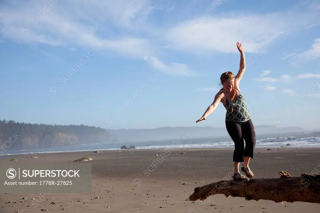 Young woman balancing on log near Third Beach in Olympic National Park, WA.