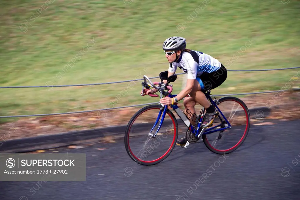 A female cyclist speeds down a road on her bike.