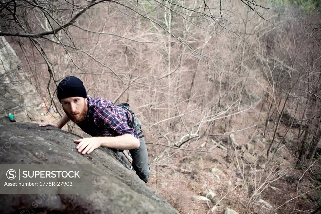 A male rock climber tops on while climbing on a cold day in the northeast.