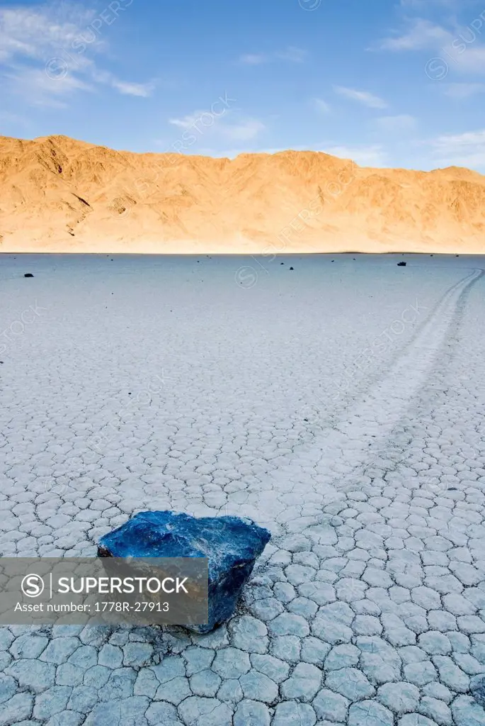 A rock leaves a trail of its movement across the The Racetrack in Death Valley National Park at sunset, CA.