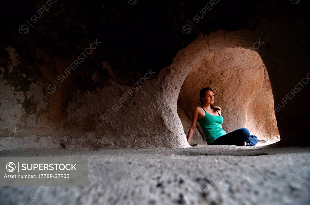 A woman sits in the famous cliff dwellings in Bandelier National Monument, NM.