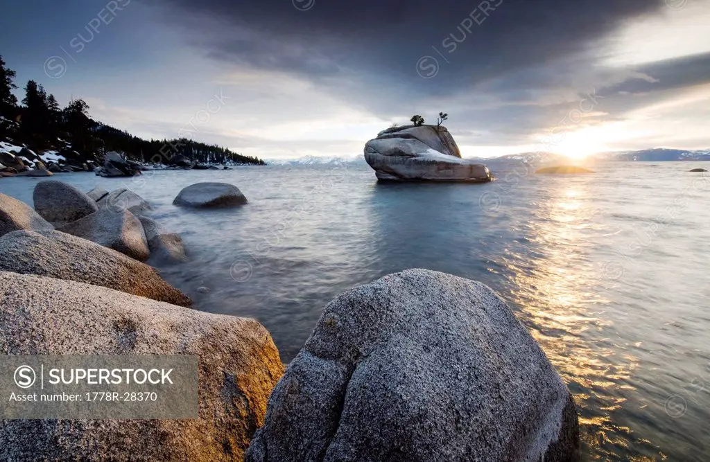 The sunset reflects off of Lake Tahoe and granite boulders on the east shore at a hidden location known as Bonsai Rock, NV.