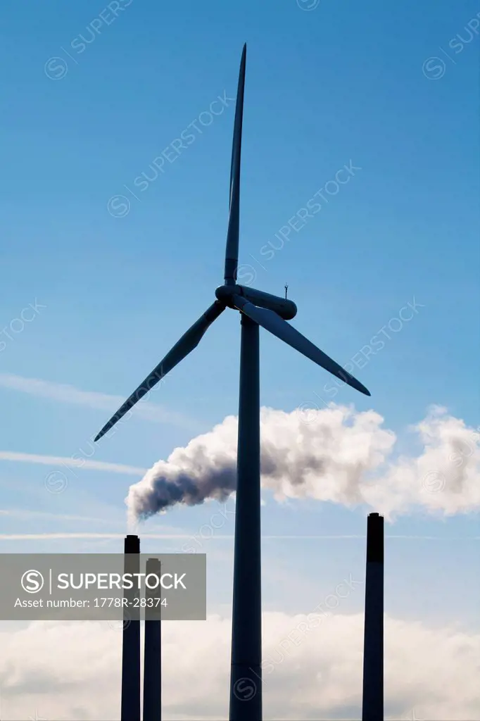 Wind turbine in front powerplant chimneys