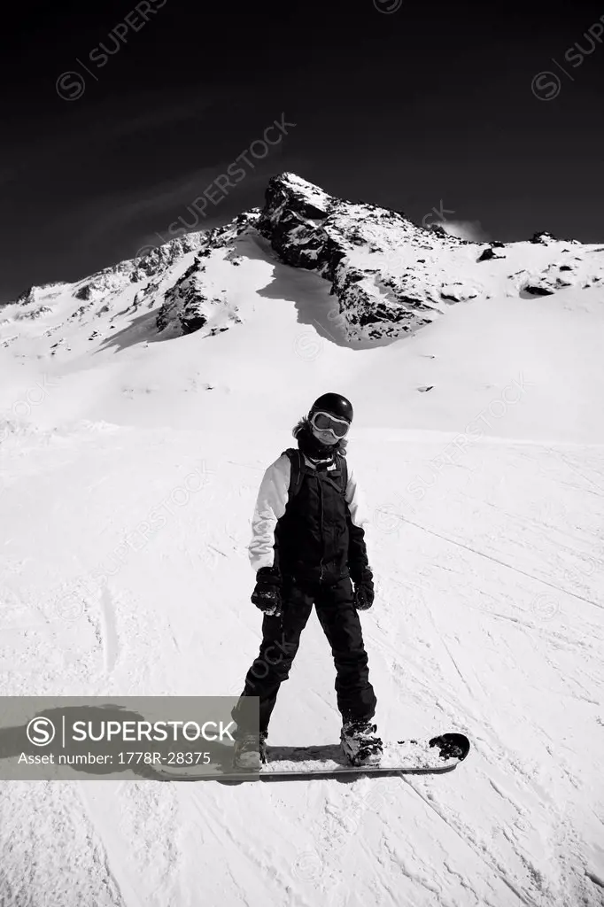Teenager standing on his snowboard in the French Alps
