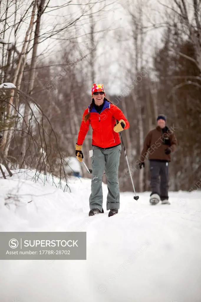 A young woman skiis along a wooded trail in the mountains of western Maine