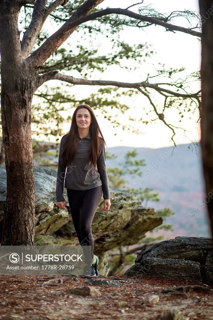 A young woman smiles at the camera while hiking.