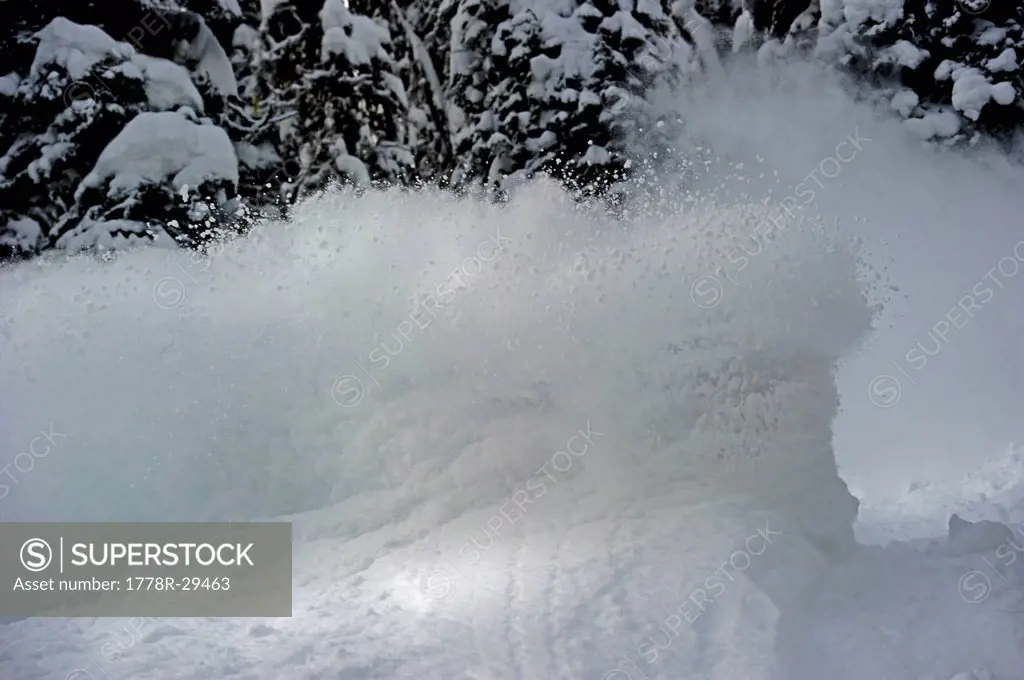 Snowboarder hiding in his own powder cloud while backcountry snowboarding.