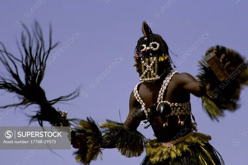 A Dogon man in his traditional costume as he dances during a celebration, Africa.