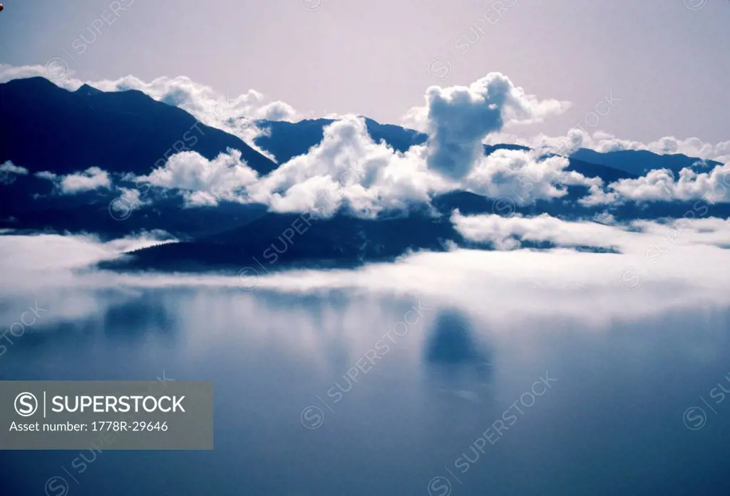 A majestic view of clouds swirling above the mountains near Glacier Bay, Alaska, USA.