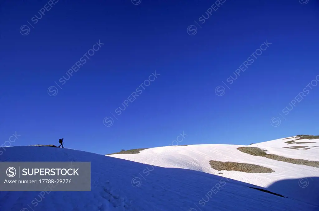 A distant view of a man walking on a snowy hillside, Wyoming, USA.