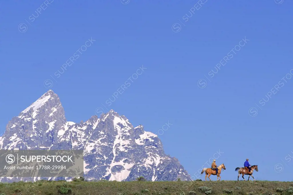 Two people on horse back, Teton Mountain, Wyoming, USA.