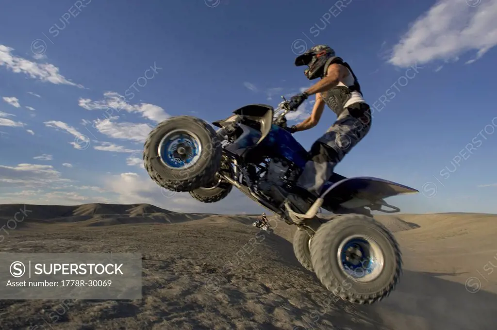 Man jumping a four wheel quad off road in the Southwestern USA .